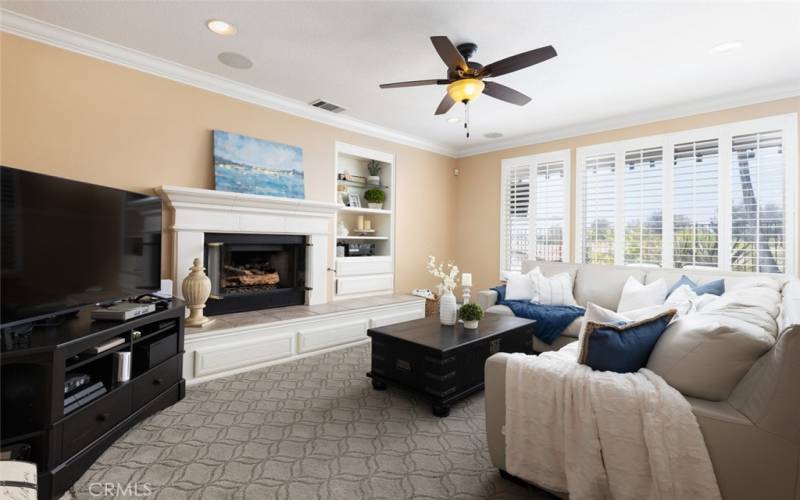 The family room includes a fireplace, ceiling fan, and built-in shelving.