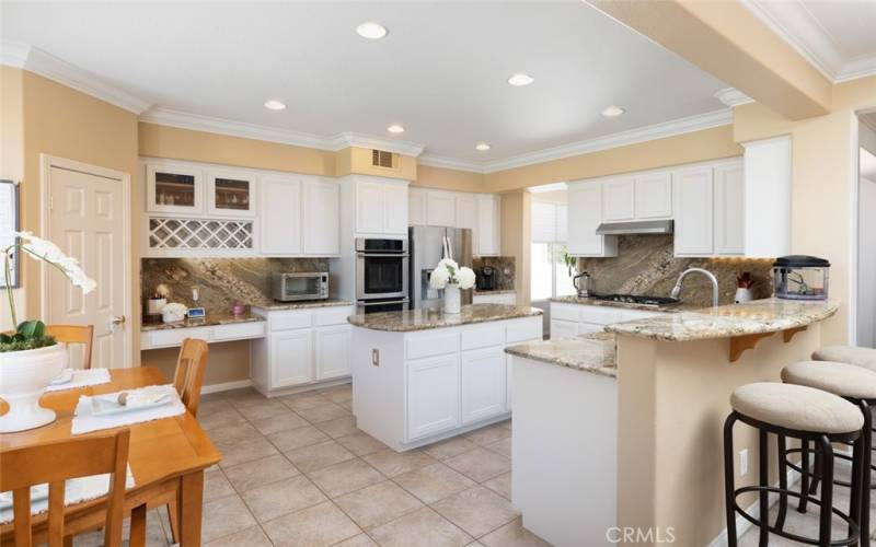 The beautiful kitchen is equipped with white cabinets, stainless steel appliances and a pantry.