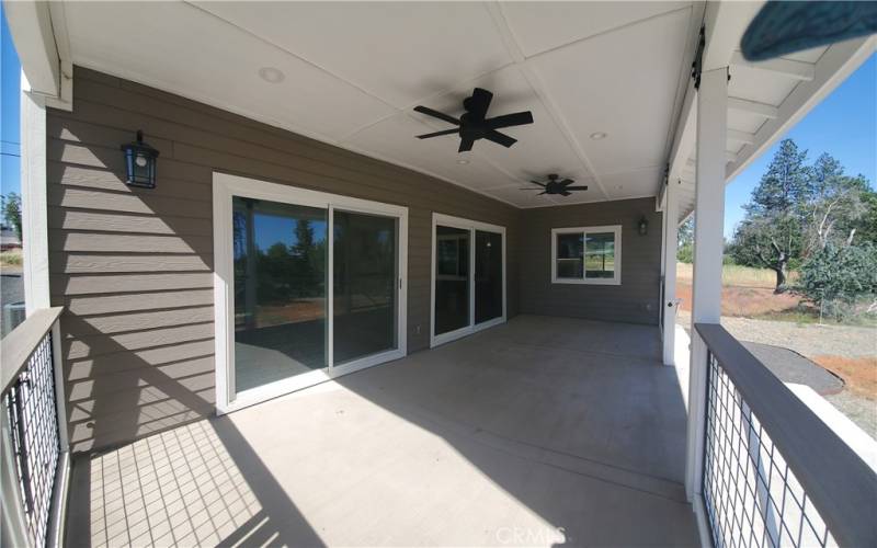 View of covered back patio with oversized sliding glass doors leading to bonus room & living room.