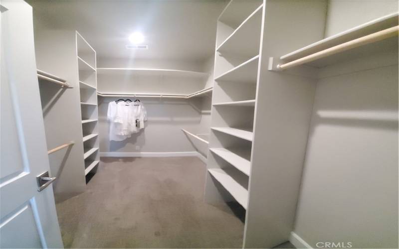 View of walk-in closet with custom shelving in private primary suite.