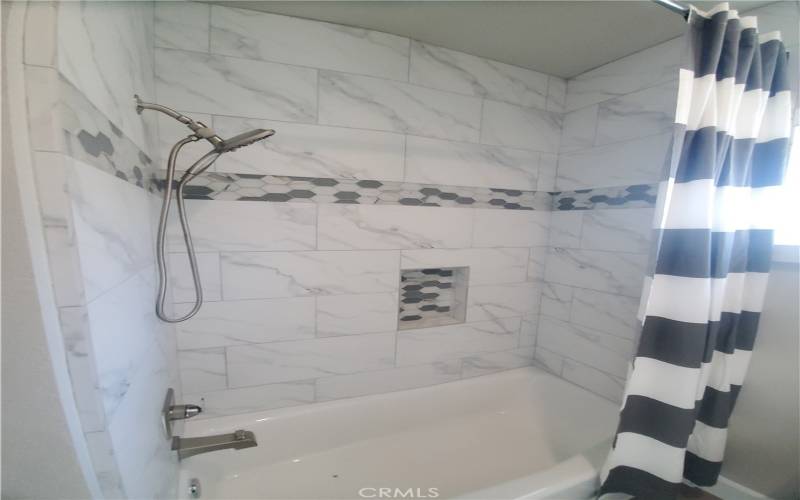 Guest bathroom shower/tub with custom tile.