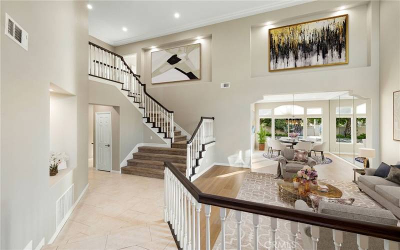 Front entryway opens to soaring ceilings, an impressive staircase, a living room, and formal dining room.