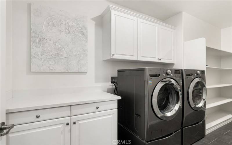 This laundry room is HUGE with a ton of shelving and cabinetry.