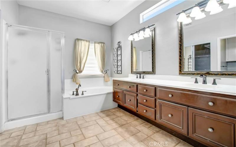 Tiled master bath with dual sinks, soaking tub and shower. Nicely decorated with lighting, mirrors and custom faucets.  Lots of cabinet storage. Mirrored walk-in closet is to the left.