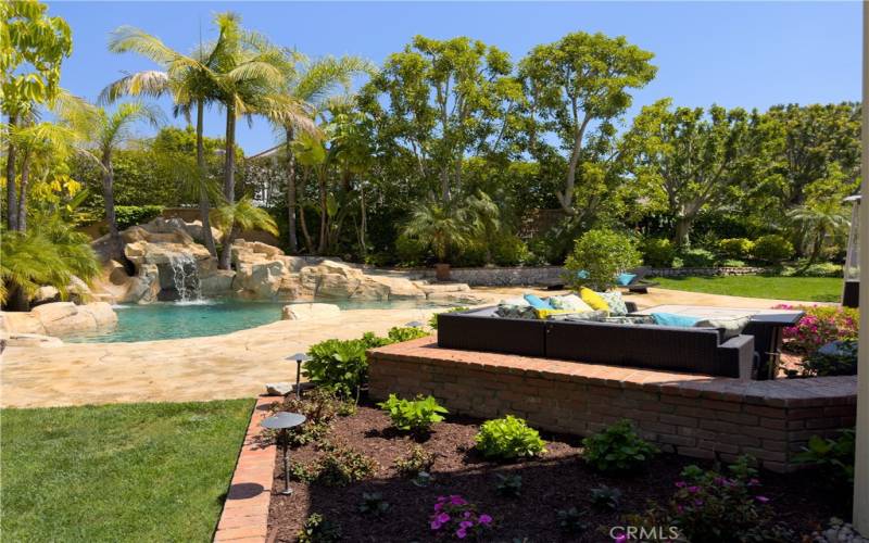 Backyard, with large expanses of Green Grass and Pool, with Waterfall and Slide