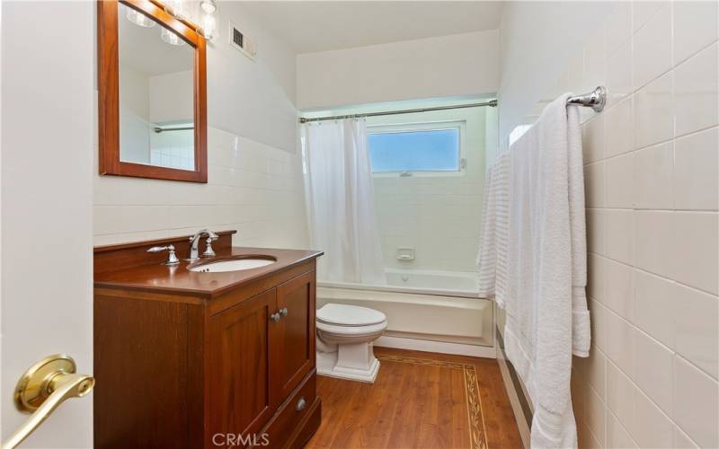 The centerpiece of the bathroom is a spacious tub/shower combination, surrounded by sleek tile walls that exude contemporary charm.