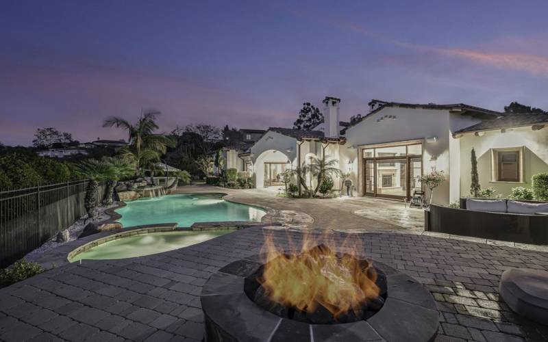 Wonderful entertainer's yard with raised patio with fire pit and resort pool, water feature and gorgeous onyx clad built in bbq bar