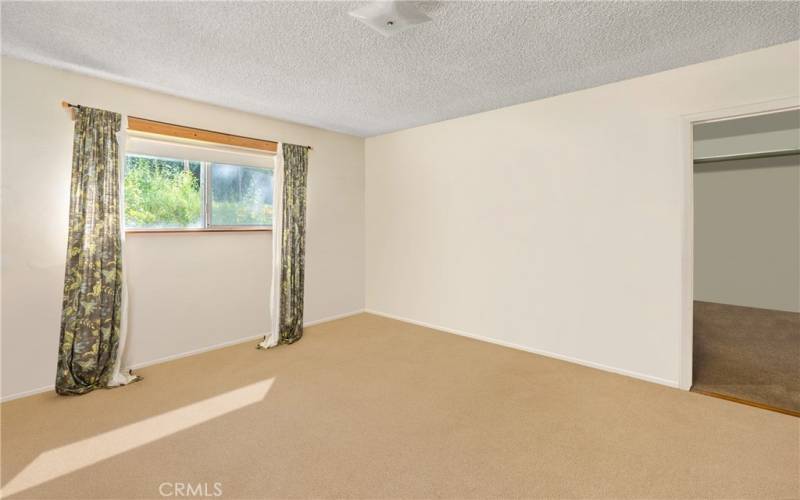 Primary bedroom with view of back yard .Photo has been virtually edited to remove seller's personal property.
