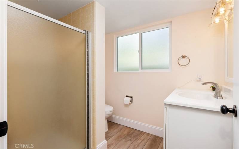 The bathroom features a walk-in shower and laminate wood floors.