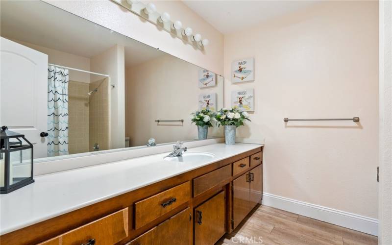 The main bathroom has a large vanity, laminate wood floors and a tub/shower combination.