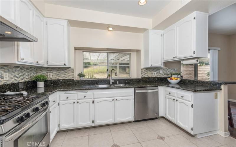 Updated kitchen with granite countertop, backsplash, bay window and ample cabinets.