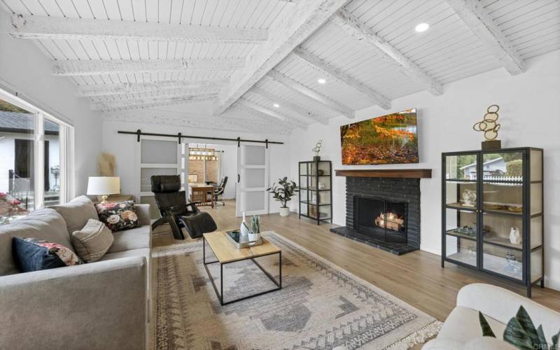 Vaulted wood ceilings and fireplace with large picture window looking to front yard