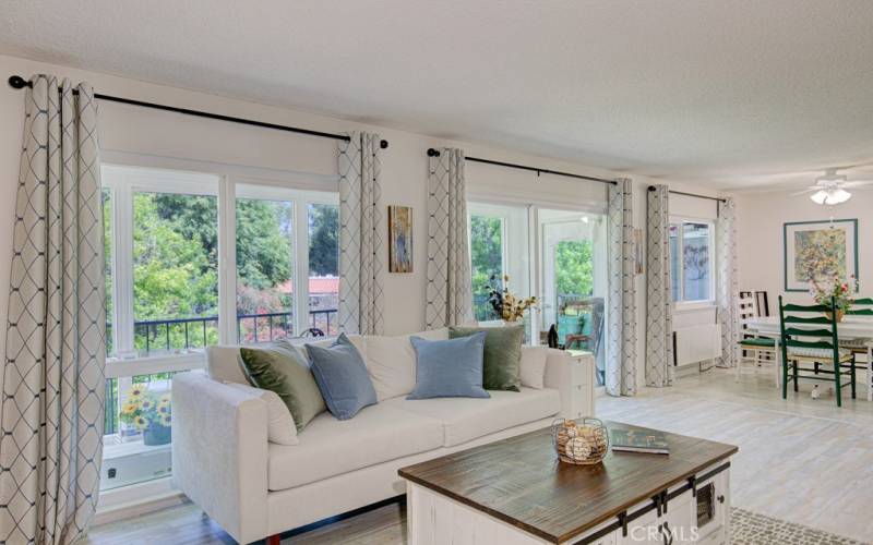 Another view of the living room looking towards the enclosed balcony with easy access through a sliding glass door. Dining room can be partially seen at right.