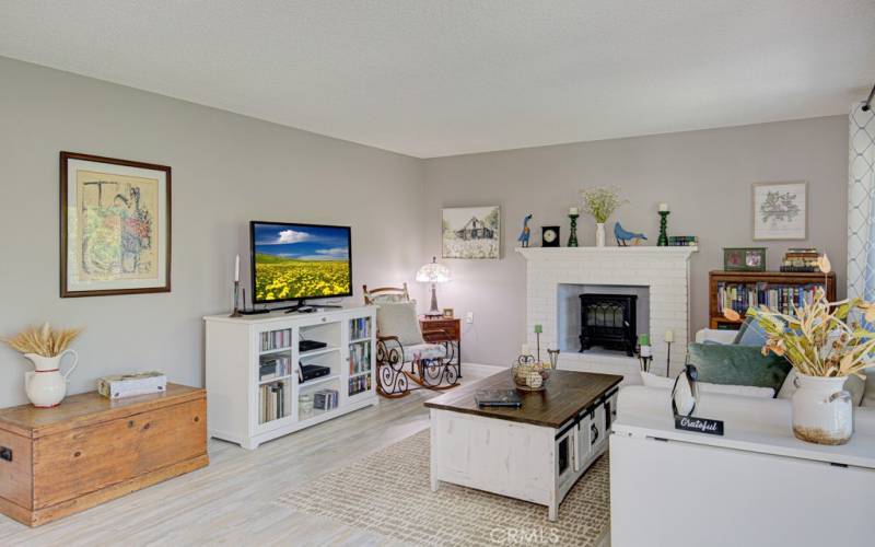 Another view of the living room. Note the neutral colored walls and attractive wood-like vinyl flooring.