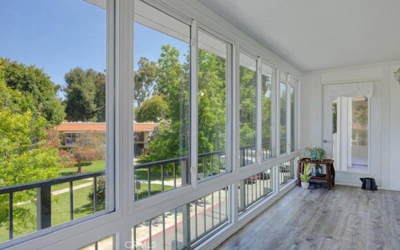 Lovely enclosed balcony features a stunning panoramic view of the neighborhood and countless trees.