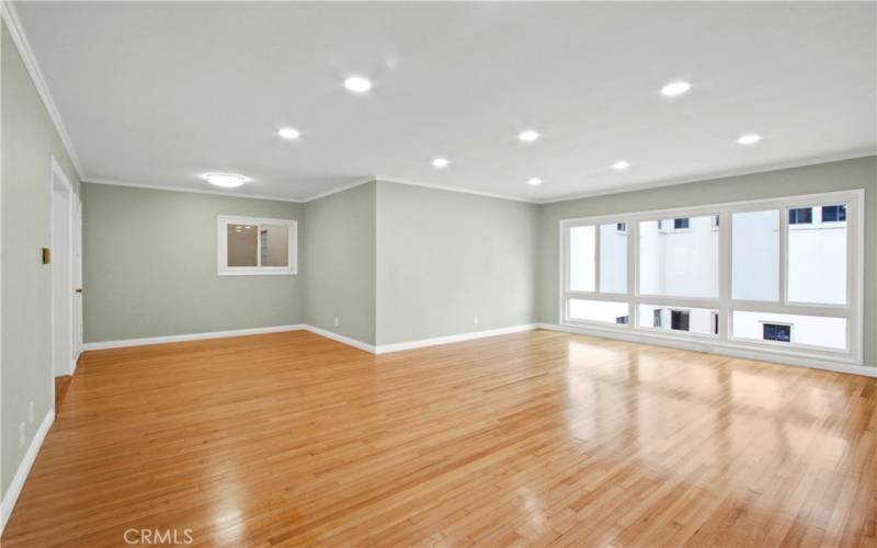 Expansive living room with gleaming hardwood floors, new windows and recessed lighting.