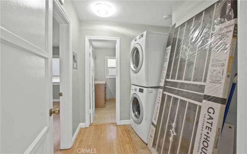 Large and wide hallway with stackable laundry which leads to bathroom and bedroom, extra storage too