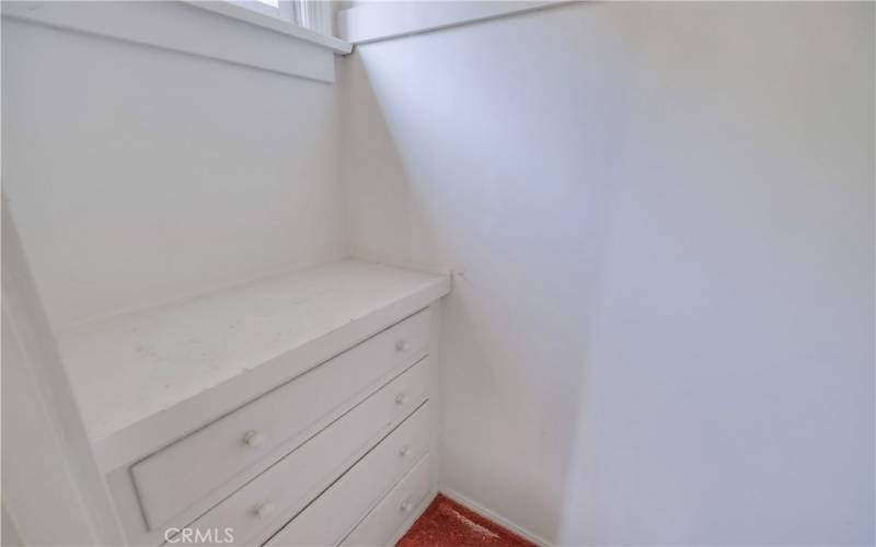Walk in closet with built in drawers and window for light.