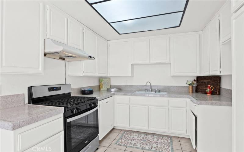 Tiled kitchen counters, flooring and new stove with a newer dishwasher as well. Lots of cabinet space