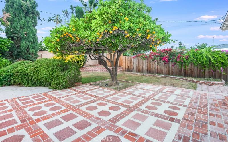 The beautiful lush backyard will be a favorite entertainment destination with its sparkling in-ground pool, open patio, attractive raised brick planters, well-trimmed hedges, separate grassy area, and mature lemon and orange trees.