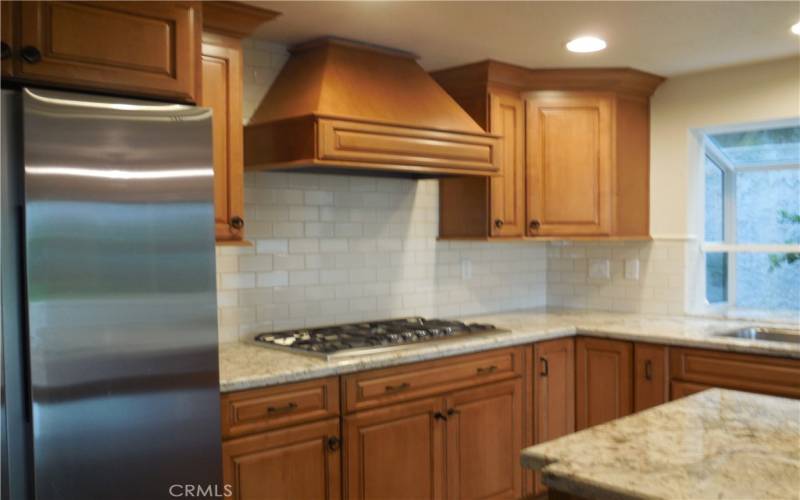 Remodeled kitchen with stainless steel ref and 5 burner gas stove top
