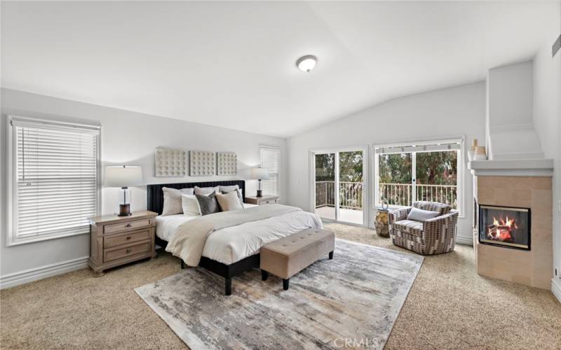 Luxurious master bedroom with vaulted ceilings, fireplace, and a deck to enjoy the view