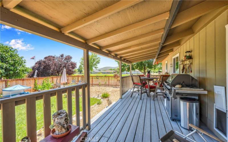 Inviting covered back deck overlooking fenced backyard.