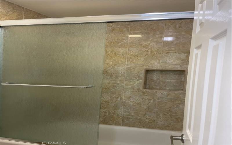 Beautiful custom stone tiled shower with privacy glass sliding door