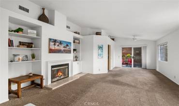Living room with shelving both sides of the gas fireplace and towards the dining room and backyard