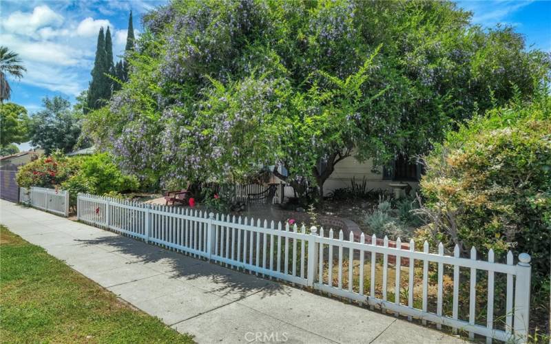 White Picket Fence & Side Angle of Front of Property with Lots of Shade