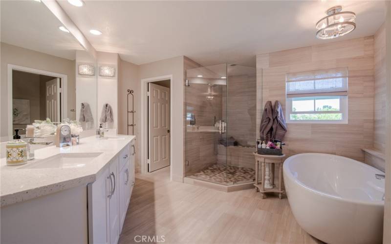 Stunning primary bathroom that has been remodeled with marble floors, dual vanity, glass enclosed shower, soft close cabinets, freestanding tub and a walk-in closet with built-ins.