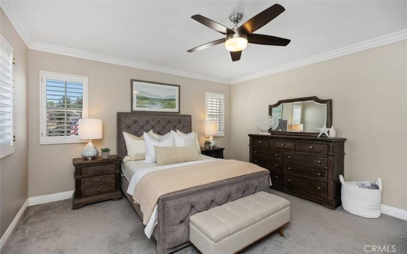 Master bedroom with wood shutters and ceiling fan.