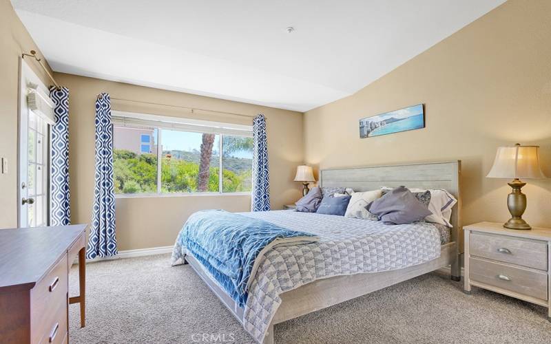 The primary bedroom has vaulted ceilings, a balcony and a view of the lush hills.