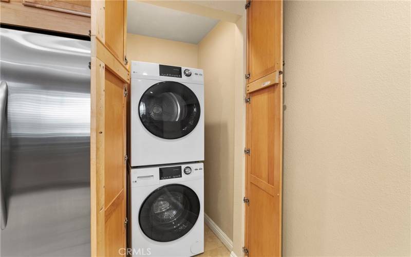 Washer and dryer next to the refrigerator are hidden behind matching cabinet doors.
