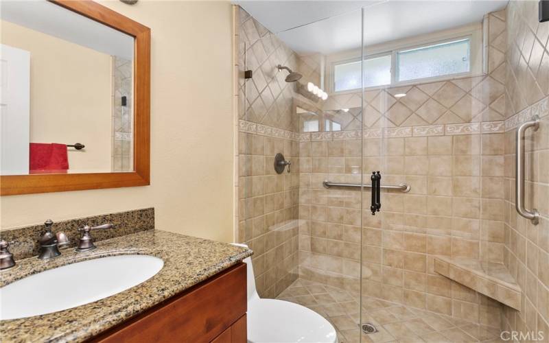 Hall bath has titled shower with a seat. Granite countertop
