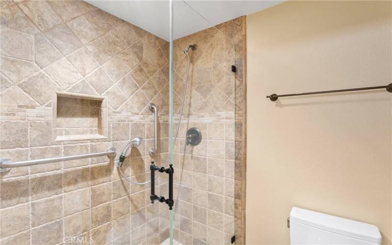 Primary bathroom has tiled shower with seat and handheld showerhead