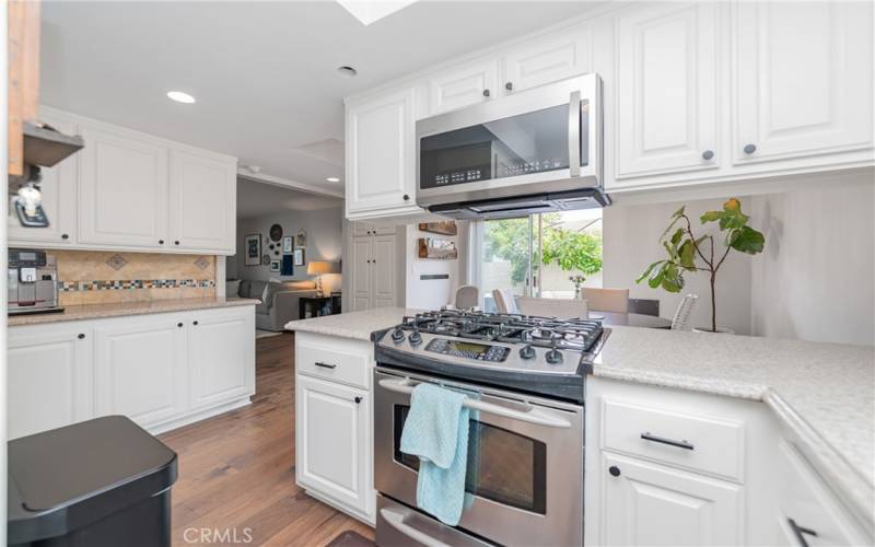 Step into this stunning, modern kitchen with sleek stainless steel appliances, ample cabinet space, and beautiful hardwood floors. Enjoy your meals in the bright and airy dining area with a view of the lush backyard, perfect for both everyday living and entertaining guests.