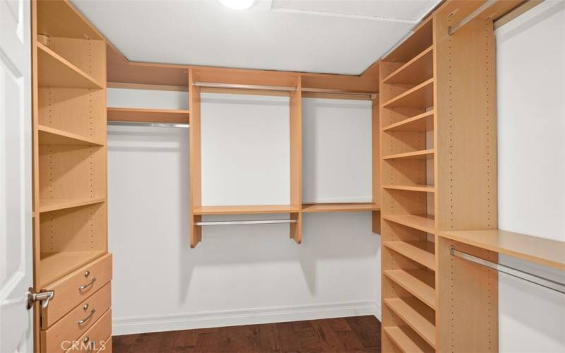 Primary walk in closet with custom build in shelves & drawers.
