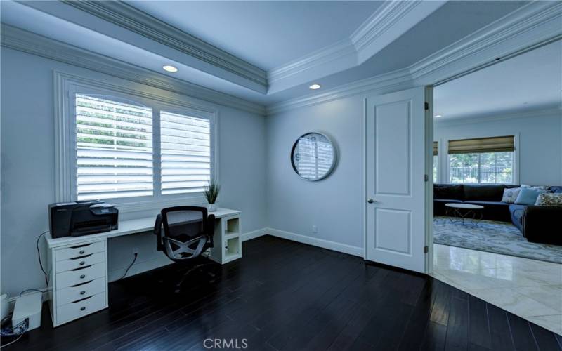 Downstairs study/ music room/ library has coffered ceiling, shutters on the window and beautiful dark flooring.