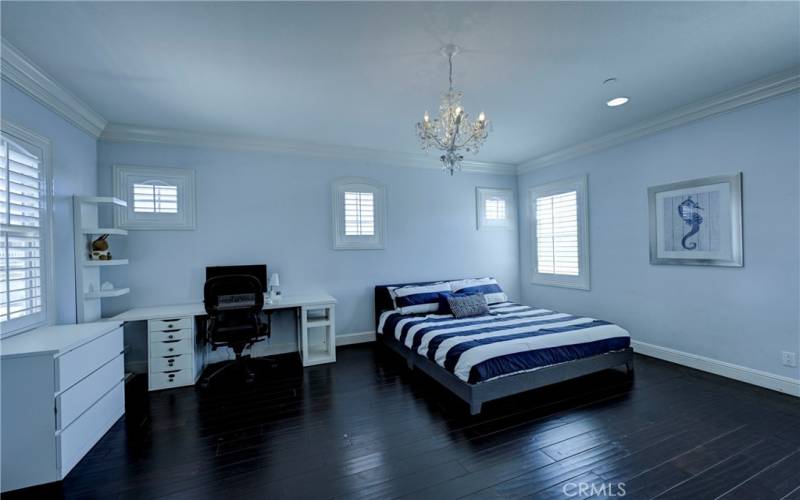 Upstairs ensuite bedroom #3 with beautiful flooring, crown molding, pretty chandelier and shuttered windows.