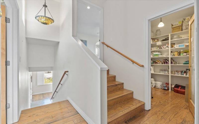 pantry, stairs up to the primary bedroom and stairs leading down to the family room and garage entry, laundry located to the left