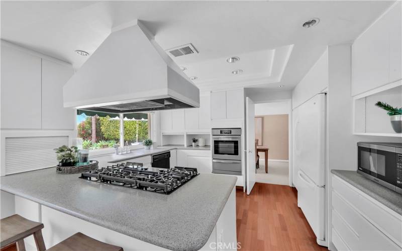 the well-appointed kitchen, featuring an abundance of pretty white cabinetry and modern appliances including a refrigerator, microwave, dishwasher, gas stove top, and separate newer oven.