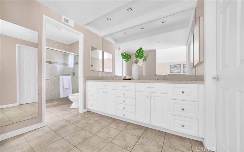 The bathroom features dual sinks, ample storage, recessed lighting