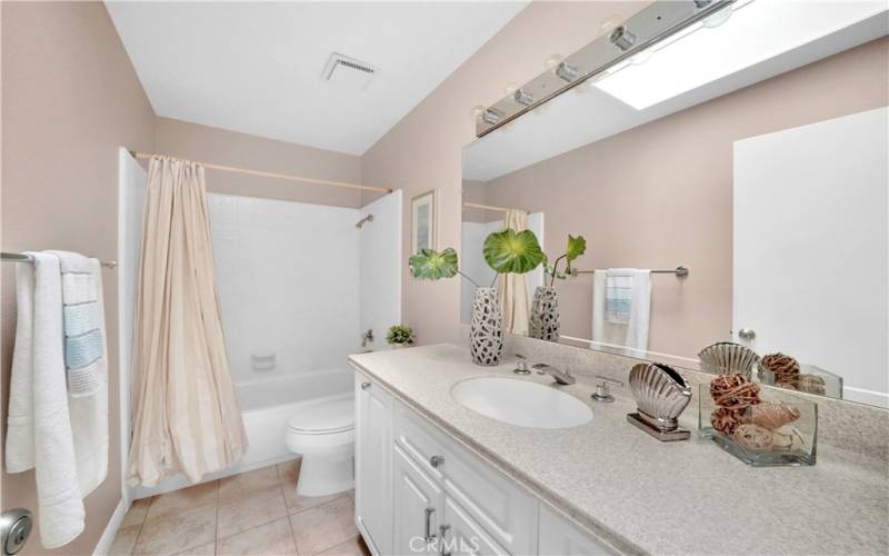The upstairs guest bathroom, complete with a skylight, features a tub/shower combo with custom tiled surround.