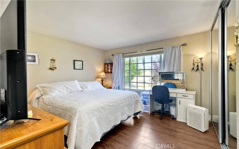 Primary bedroom with pergo style flooring and dual mirrored wardrobes