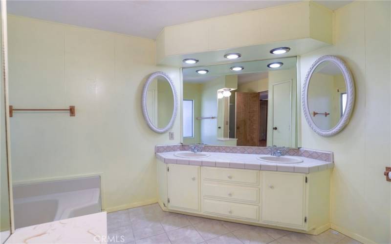 The ensuite bathroom has tiled floors and a large vanity with two sinks.