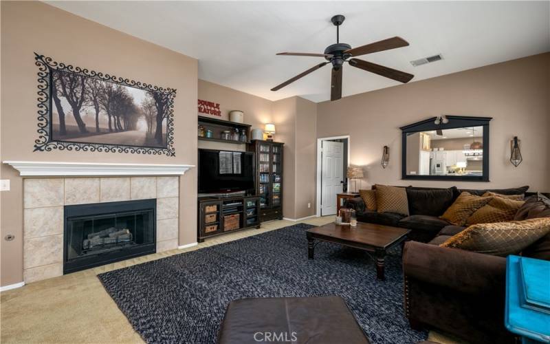 Family room with fireplace and ceiling fan.