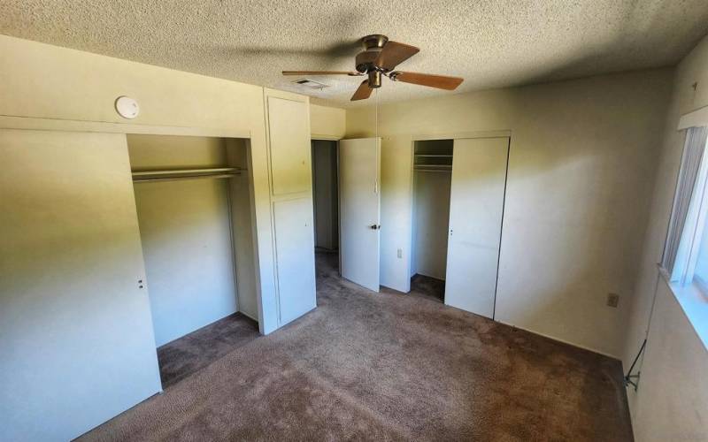 Large primary bedroom has dual closets and view of the rear yard.