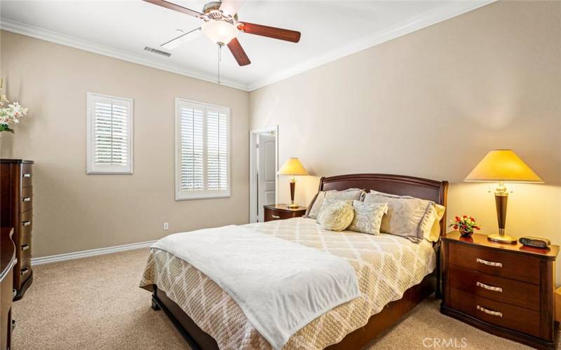 Bedroom with recessed lights, ceiling fans, crown moldings, and carpet.