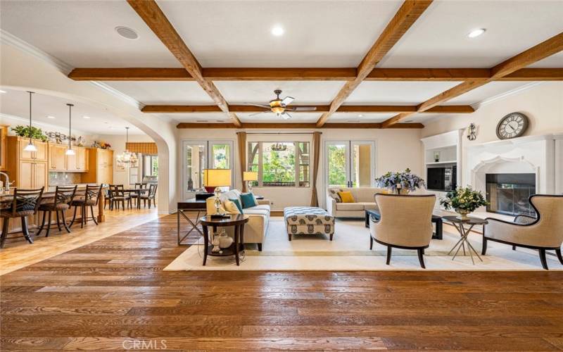 Family room with custom coffered ceiling, fireplace and built-in media shelves, and premium oak floor.